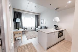 a white kitchen and living room with a table at Forenom Hotel and Apartments Vantaa Tikkurila in Vantaa