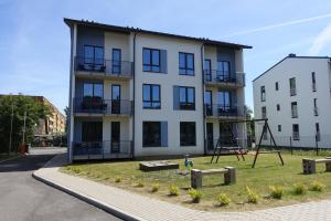 un gran edificio blanco con un parque infantil delante de él en Raua 15 Apartment en Tartu