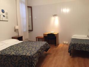 a hotel room with two beds and a desk at Hotel Caneva in Venice