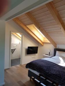 a bedroom with a bed and a flat screen tv at Schatzbergalm Pension in Dießen am Ammersee