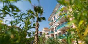 Un edificio alto con una palmera delante. en Villa Romana Fréjus, en Fréjus