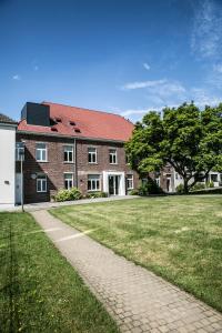 een bakstenen gebouw met een boom en een grasveld bij De Kleppe in Everbeek