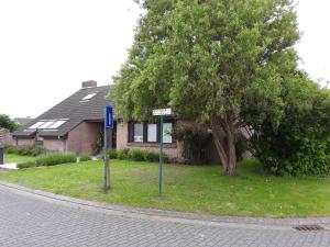 une maison avec un arbre et deux panneaux de rue devant elle dans l'établissement Westhinder, à Wenduine