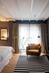 een slaapkamer met een bed, een stoel en een raam bij suite no 7 in Amsterdam