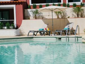 a swimming pool with two chairs and an umbrella at Topazio Vibe Beach Hotel & Apartments - Adults Friendly in Albufeira