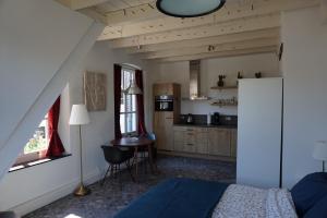 a bedroom with a bed and a table and a kitchen at B&B Appartementen Smedery in Nijmegen