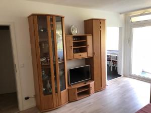 a living room with a tv and a wooden cabinet at Messeapartment Hahnenkamp in Hemmingen