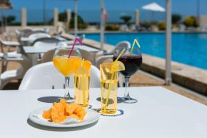 four glasses of wine and food on a table near a pool at RVHotels Nieves Mar in L'Escala
