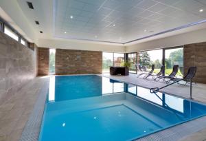 a swimming pool with blue water in a building with windows at Apartmán SUN Dolní Morava in Dolní Morava