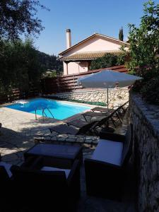 a pool with chairs and an umbrella next to a house at Evridiki's Villas in Agios Nikitas