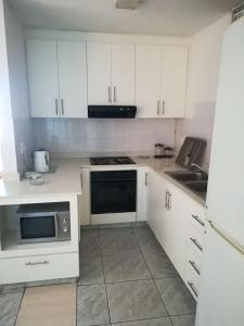 eine Küche mit weißen Schränken, einer Spüle und einer Mikrowelle in der Unterkunft Margate Boulevard 302 in Margate