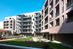 um edifício de apartamentos com um relvado em frente em Domitys La Palombine em Saint-Raphaël