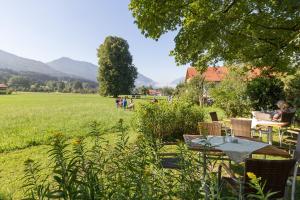 a garden with a table and chairs and a field at Landhotel Die Waldschänke in Kochel +7 photos