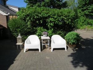 two white chairs and a table in a yard at B&B Vloedlijn Texel in Den Burg