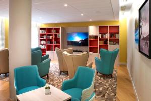a waiting room with blue chairs and a tv at Domitys La Palombine in Saint-Raphaël