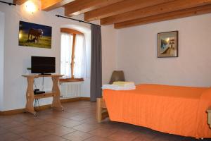 een slaapkamer met een oranje bed en een televisie bij Italo-Svizzero in Chiavenna