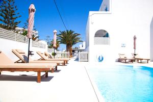 a pool with chaise lounge chairs next to a building at Oscar Hotel in Kamari