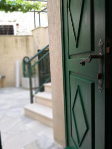 a green door with a handle on a building with stairs at Apartments Jaksic in Postira