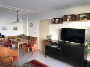 uma sala de estar com televisão e uma mesa com cadeiras em Rosenalm Penthouse 147 em Scheidegg