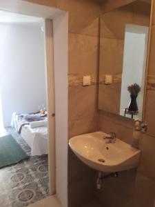 a bathroom with a sink and a mirror and a bed at Marty Apartment in Rogoznica