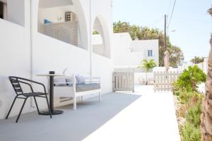 uma varanda com uma mesa e uma cadeira num edifício branco em Oscar Hotel em Kamari