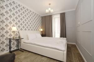 1 dormitorio con cama blanca y ventana en City Center - AURA by Apartmore en Gdansk