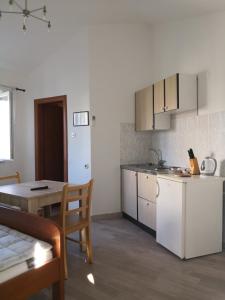 eine Küche, ein Esszimmer mit einem Tisch und einem Tisch sowie eine Küche in der Unterkunft Apartments Jaksic in Postira