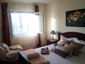 a bedroom with a bed and a chair and a window at Marty Apartment in Rogoznica