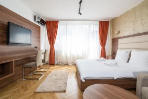 a hotel room with a bed and a flat screen tv at Central Park Apartments in Belgrade