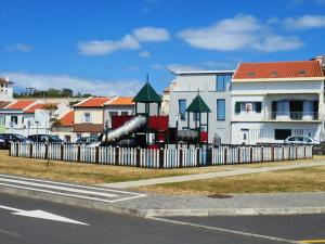 uma cerca em frente a uma casa com um escorrega em Casa da Flor em Ponta Delgada