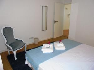 um quarto com uma cadeira e uma cama com toalhas em Casa da Flor em Ponta Delgada