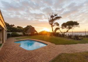 una piscina con puesta de sol en el fondo en My Den Beachfront B&B and Self-Catering, en Port Shepstone