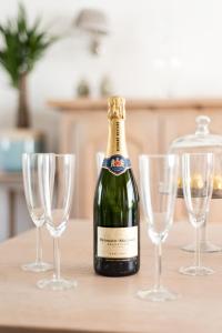 eine Flasche Champagner auf einem Tisch mit vier Weingläsern in der Unterkunft Lovely Guesthouse Lier in Lint