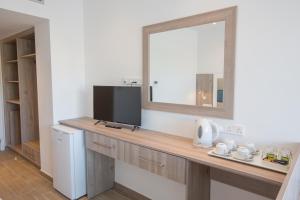 a bathroom with a vanity with a mirror and a television at Stratovarius Nissi Rooms in Ayia Napa