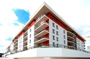 an apartment building with red and white balconies at Domitys Les Deux Lacs in Rumilly