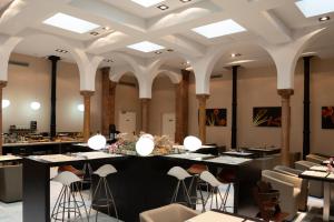 un ristorante con sgabelli e tavoli in una stanza con soffitti di Petit Palace Plaza Málaga a Málaga