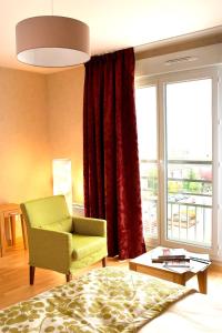 a living room with a green chair and a window at Domitys Les Deux Lacs in Rumilly