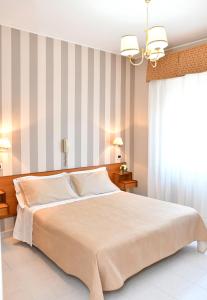 una camera con un grande letto e una parete a righe di Hotel Marconi a Fiuggi