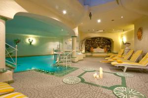 um quarto de hotel com uma piscina e cadeiras e uma lareira em Landhotel Römerhof em Dorfgastein