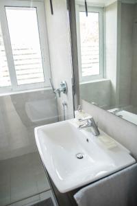 a white bathroom with a sink and a mirror at Villa Dimos in Gythio