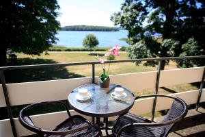 una mesa y sillas en un balcón con vistas al agua en Hotel Skanderborghus en Skanderborg