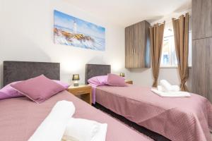 2 Betten in einem Schlafzimmer mit rosa Bettwäsche in der Unterkunft Tranquility and Nature in 4 Bedroom with Sea View in Mokošica