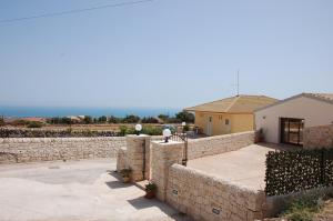 a house with a stone wall and a building at villa bove in Marina di Ragusa