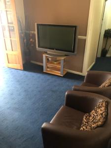 a living room with two chairs and a flat screen tv at Charde Guest House in Birmingham