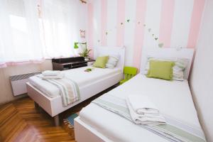 2 Betten in einem Zimmer mit rosa und weißen Streifen in der Unterkunft Apartment Ema in Šibenik
