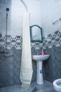 bagno con tenda per la doccia e lavandino di Kutaisi Best Guest House a Kutaisi