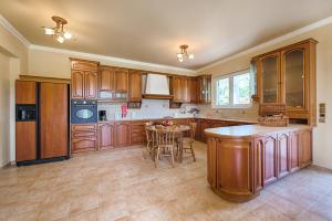 a large kitchen with wooden cabinets and a table at Royal Classico Villa in Kolimbia +35 photos
