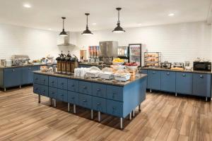 a kitchen with blue cabinets and a counter with food at Country Inn & Suites by Radisson, Baxter, MN in Baxter