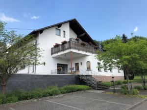 a white house with a balcony and stairs at Gästehaus Rehwinkel in Allenbach
