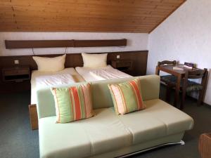 a room with a bed with a couch and a table at Gästehaus Rehwinkel in Allenbach